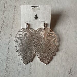 These earrings are silver-toned, laser-cut Filigree Monstera Leaf Dangle NWT